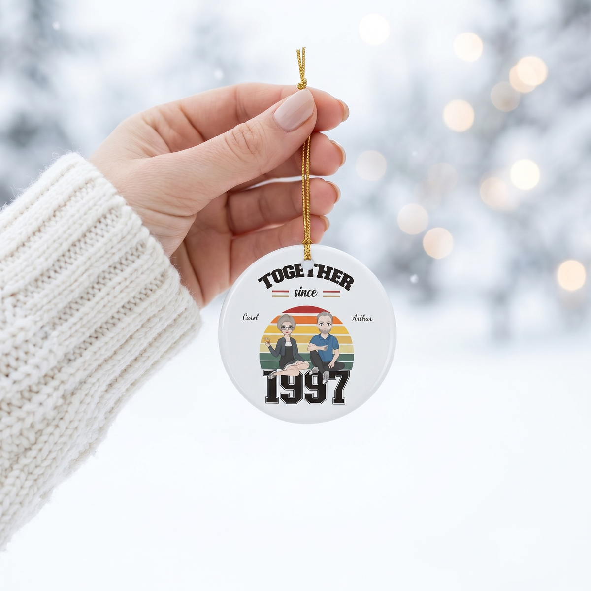 Hand holding a personalized Together Since couples ceramic Christmas ornament in a white knit sweater