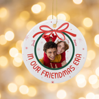 In Our Era ceramic Christmas ornament against warm golden holiday bokeh