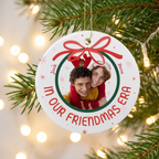 In Our Era personalized ceramic Christmas ornament hanging on a pine branch with holiday lights