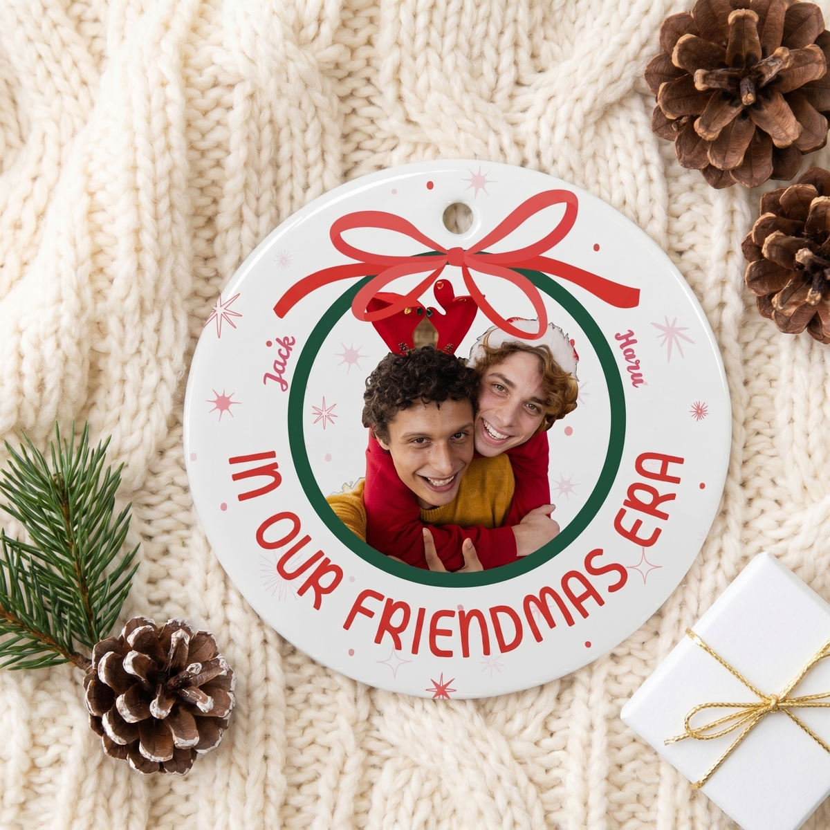 In Our Era ceramic Christmas ornament on a cream knit blanket with pine and a gift