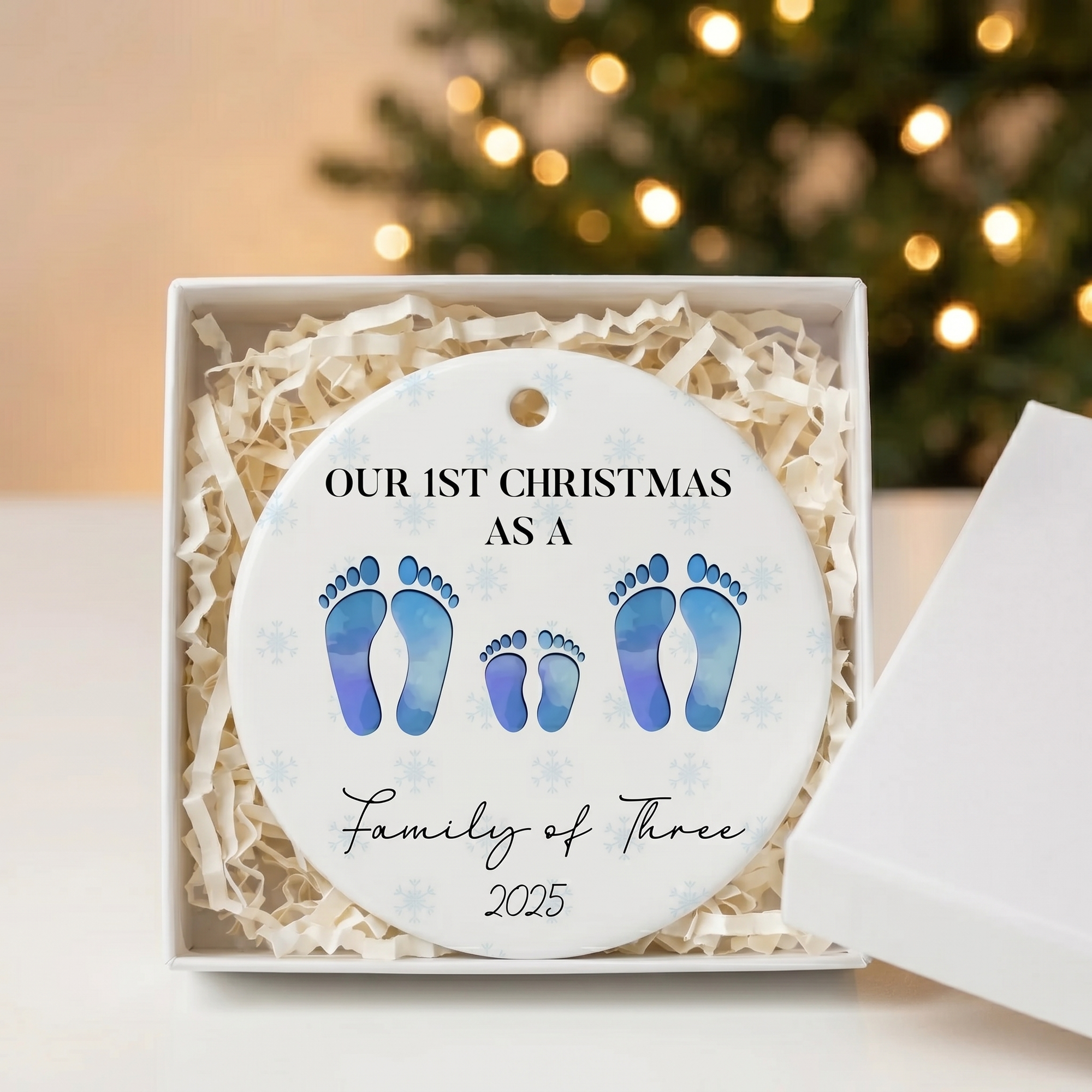 Family of four footprint ceramic Christmas ornament in an open white gift box with shredded paper