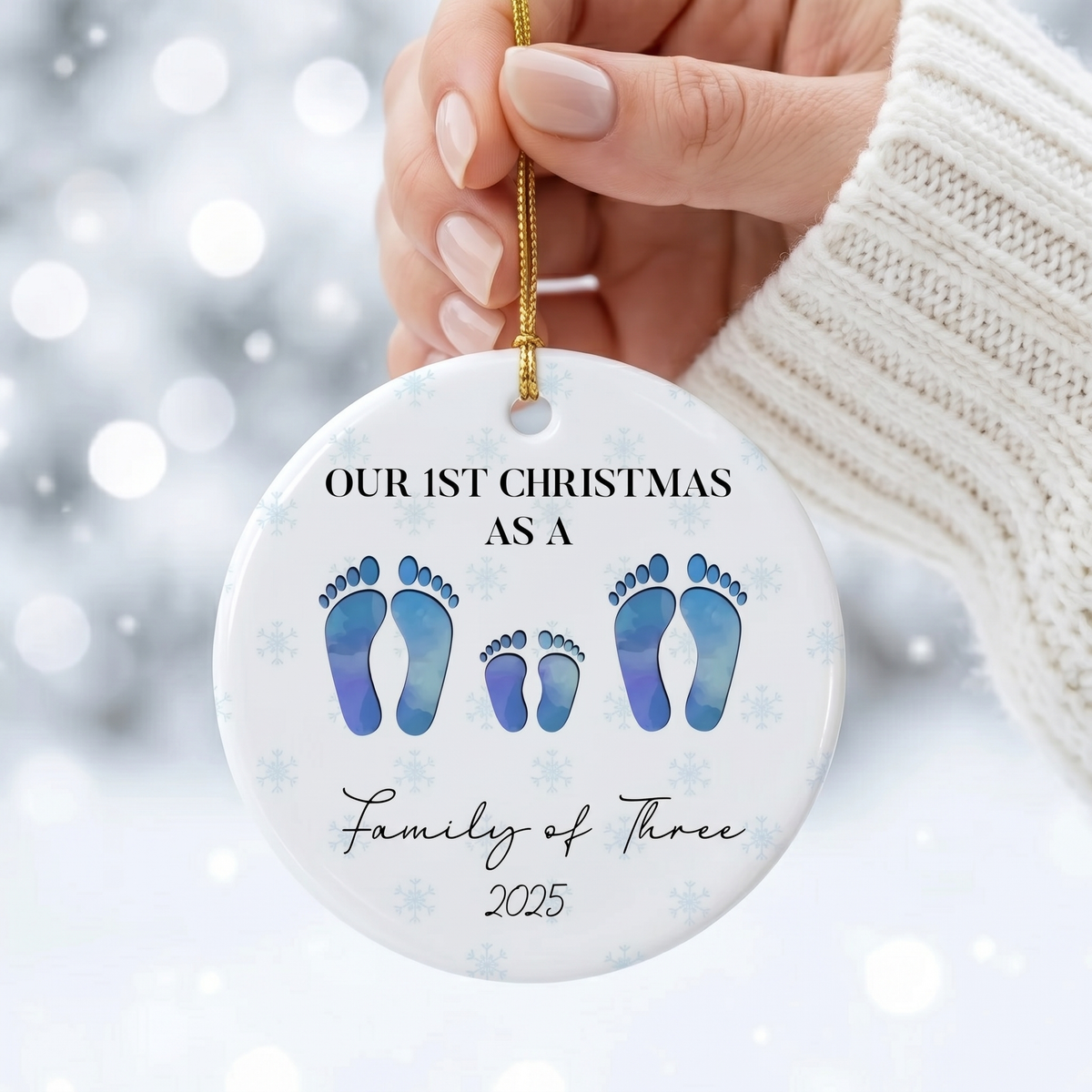 Hand holding a personalized family of four footprint ceramic Christmas ornament in a white knit sweater