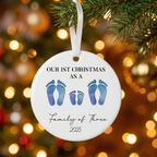 Family of four footprint ceramic Christmas ornament hanging on a pine branch with golden Christmas lights