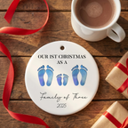 First Christmas family of four footprint ceramic ornament on a rustic wood table with cocoa