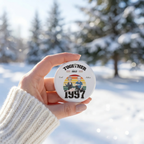 Hand holding a personalized Together Since 1997 ceramic ornament with a snowy background