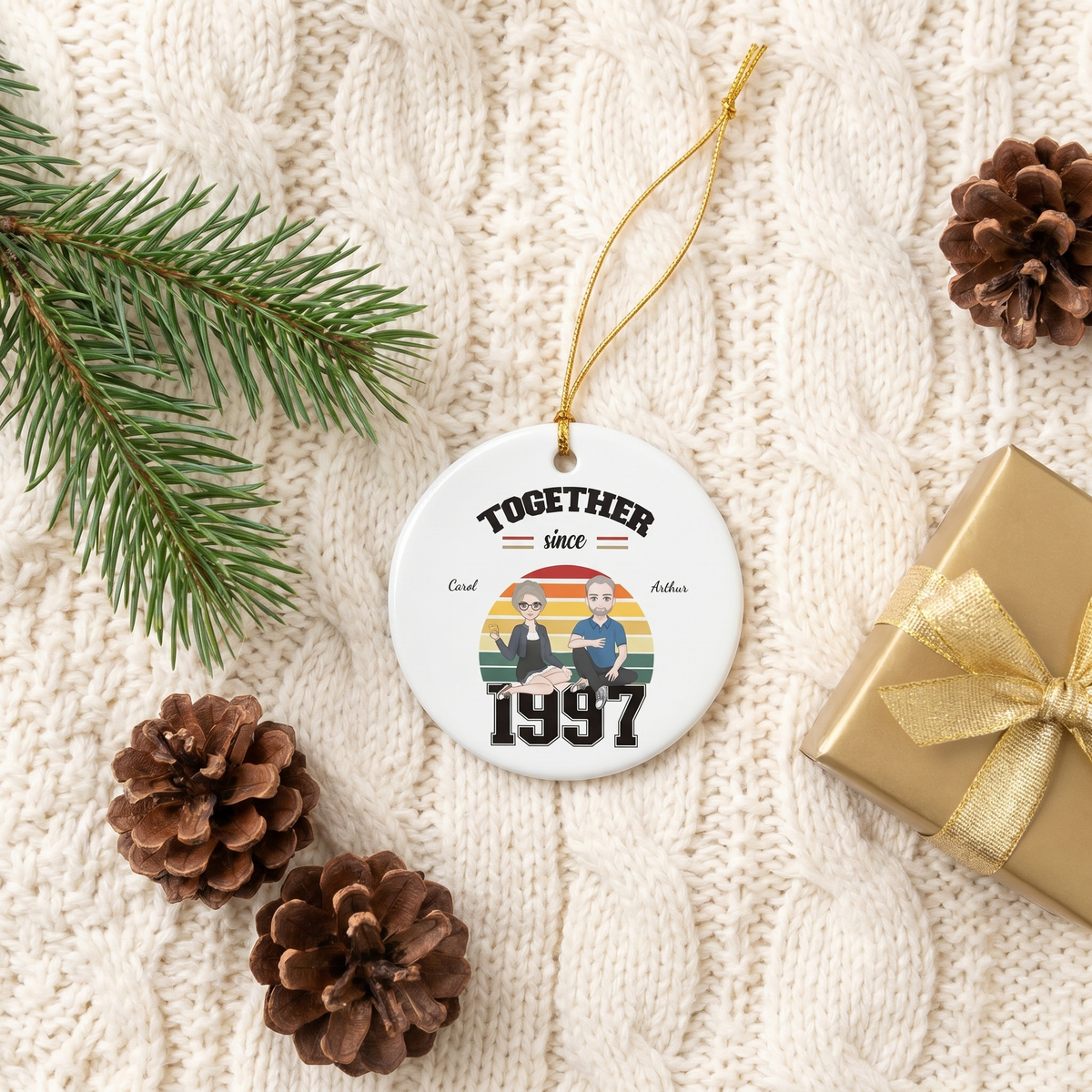 Together Since 1997 ceramic ornament flat-lay on a cream knit blanket with pinecones